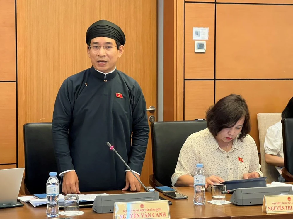 ĐB Cảnh mặc áo dài ngũ thân nam tại phiên thảo luận tổ hôm 25-5. Ảnh: C.L