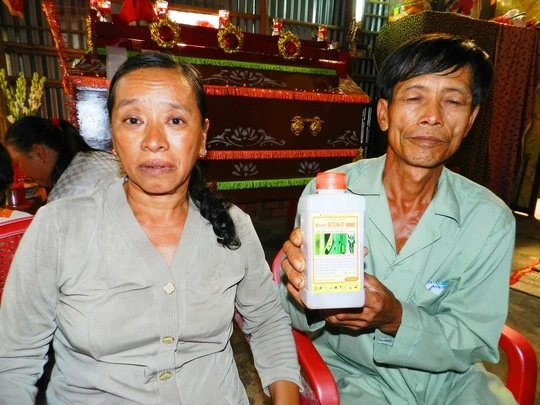 Vợ chồng ông Nguyễn Văn Tổng bên chai thuốc trừ sâu mà Kiệt dùng để tự tử