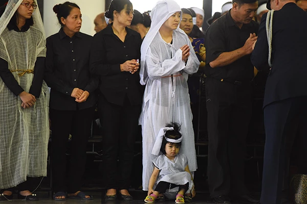 Con gái nhỏ hơn 2 tuổi của trung tá Lê Văn Đình, nhân viên tuần thám trên không ngồi bệt dưới chân mẹ.