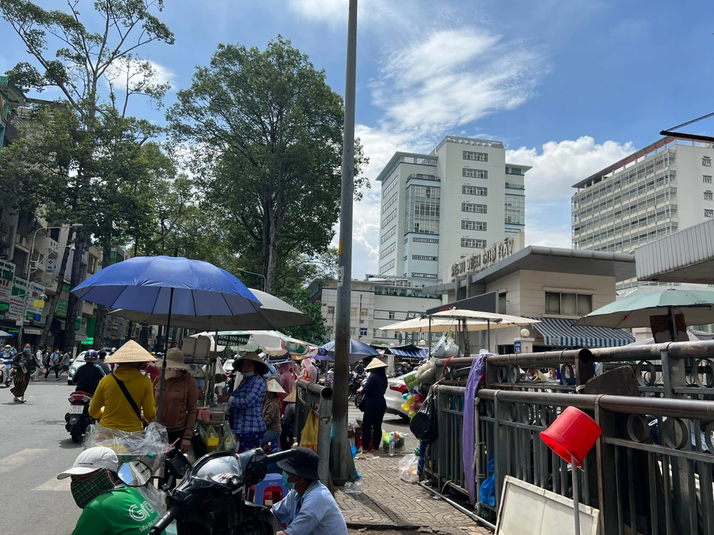 Trước cổng BV Chợ Rẫy, bãi giữ xe chiếm trọn vỉa hè, người dân tràn xuống lòng đường buôn bán.