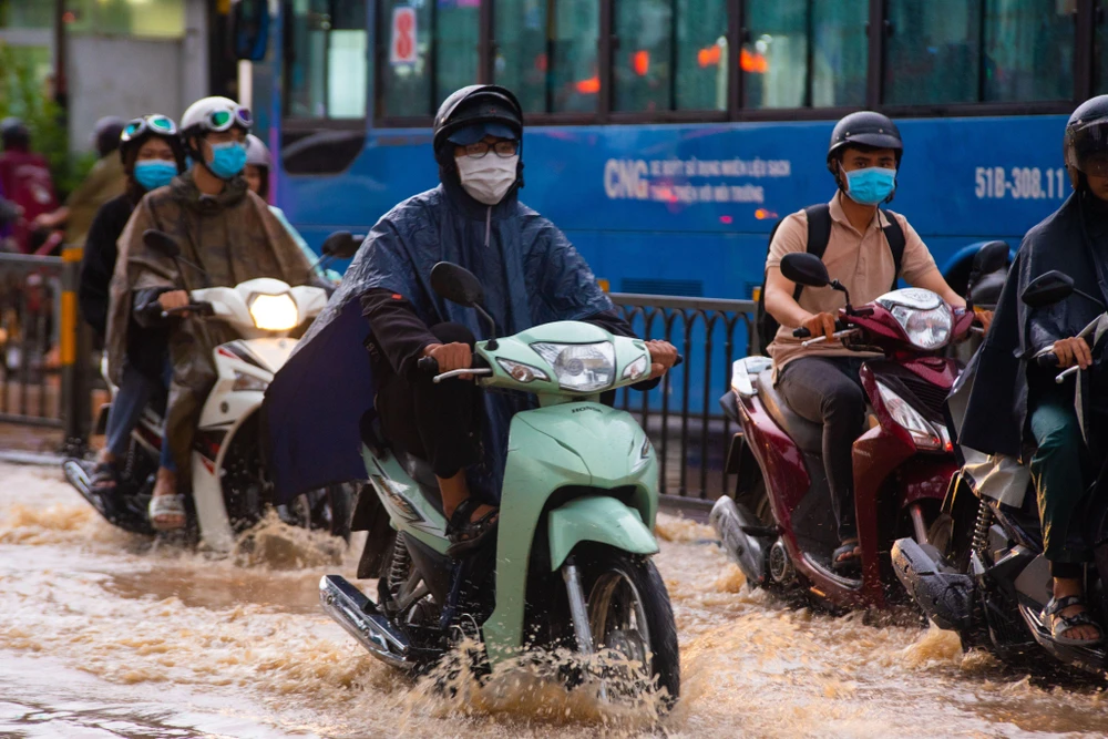 Mưa lớn, ngập sâu làm người dân đi lại khó khăn. Ảnh: HỮU HƯỚNG.