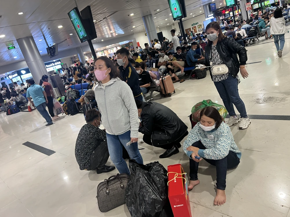 Hành khách ngồi xếp hàng chờ bay.