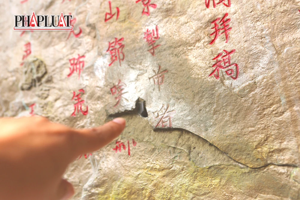Một tấm bia tạc trên vách núi còn bị khoan, đục, đóng đinh khiến hai góc chữ trên tấm bia bị biến dạng.