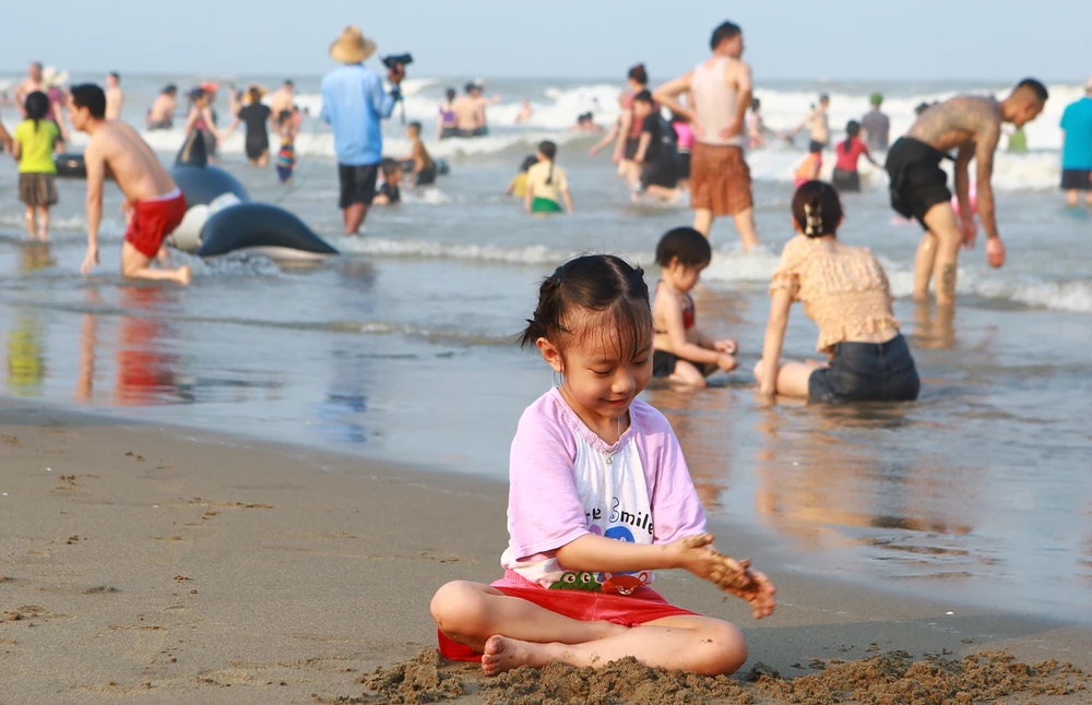 Một em bé vô tư nghịch cát bên bờ biển Sầm Sơn náo nhiệt, ồn ào. Ảnh: ĐẶNG TRUNG