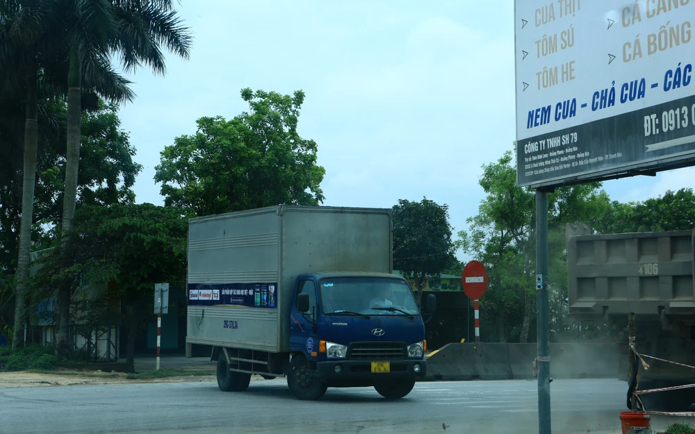 Xe tải quay đầu dứt khoát tại nút giao này, trong khi một xe tải trọng lớn vừa vụt qua đầu xe.