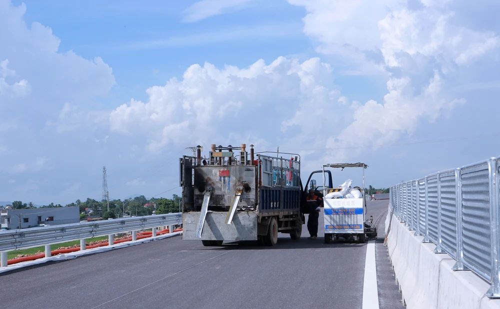 Máy móc, công nhân được huy động thực hiện làm vạch kẻ đường ngay sau khi hoàn thiện dải phân cách cứng. Ảnh: ĐẶNG TRUNG