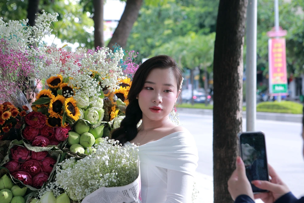 Các bạn trẻ chụp hình bên những chiếc xe đạp chở hoa mùa thu bên vỉa hè