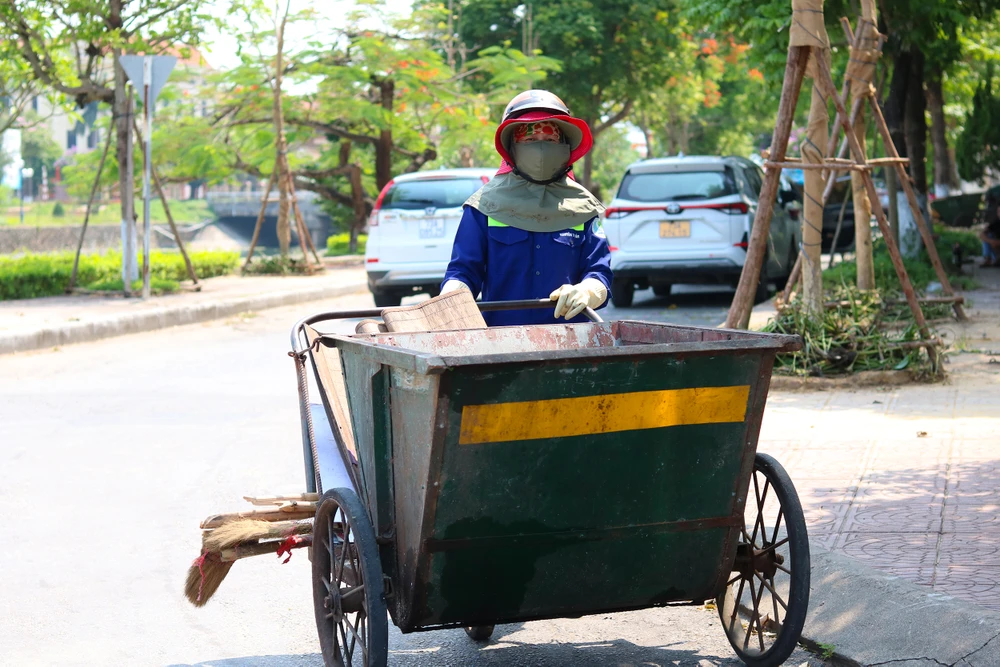 Chị Ngô Thị Bảy tất bật thu gom rác trên các tuyến đường. Ảnh: BẢO THIÊN