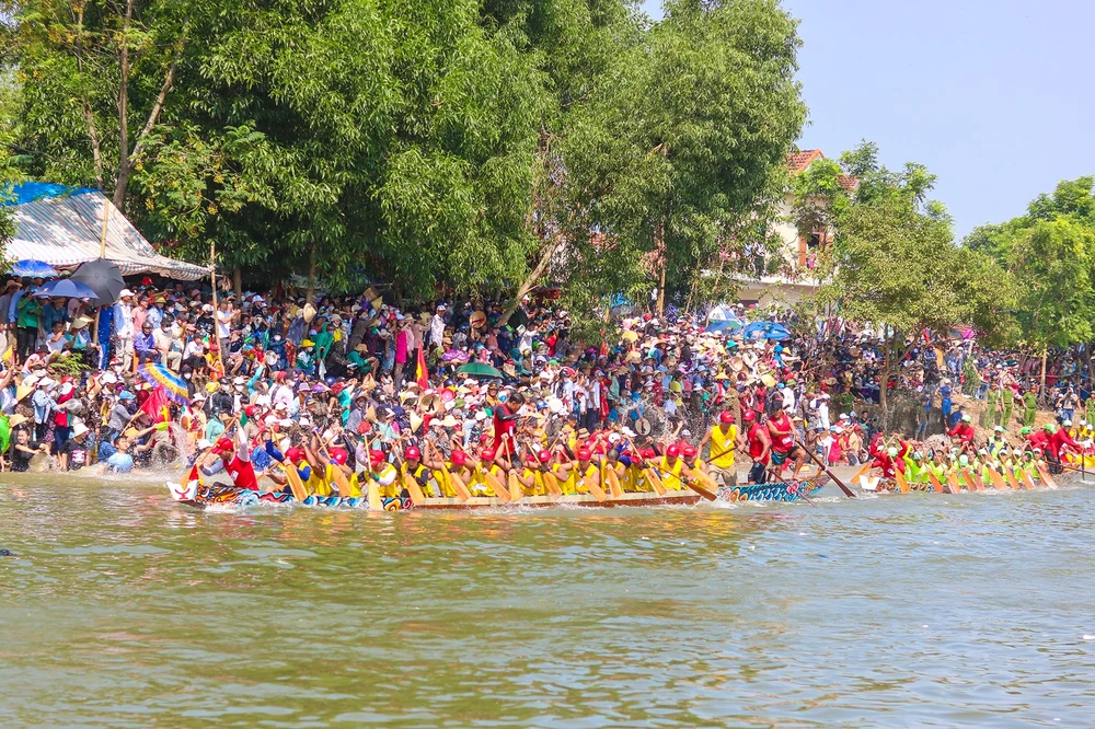 Các thuyền bơi nam ra sức tranh tài, hai bên bờ người dân hò reo cổ vũ. Ảnh: BẢO THIÊN