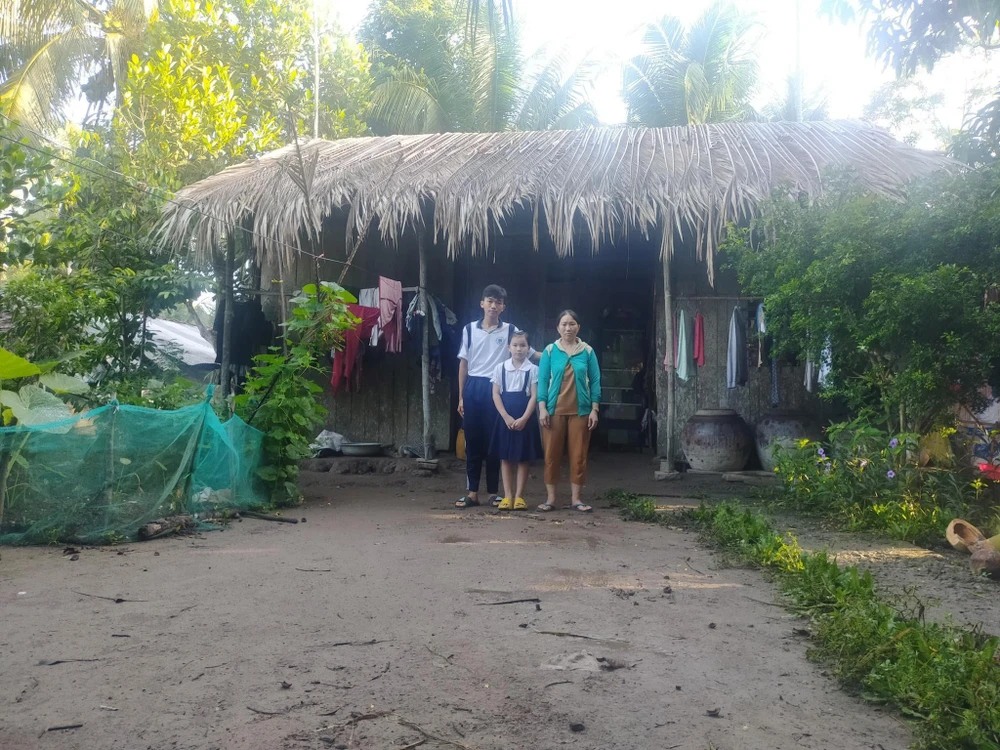 Em T.Q.Đ cùng mẹ và em gái trước căn nhà lá của gia đình Em T.Q.Đ cùng mẹ và em gái trước căn nhà lá của gia đình