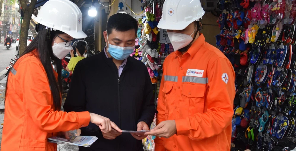 Nhân viên EVNHANOI phát tờ rơi tuyên truyền tiết kiệm điện.