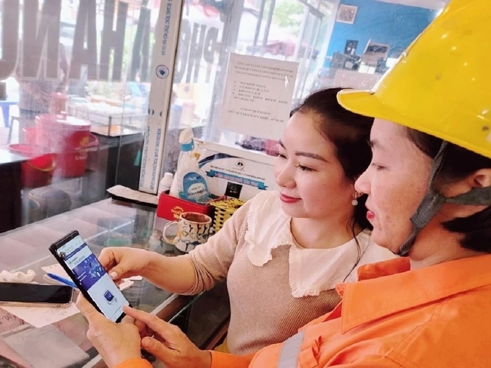 Nhân viên điện lực hướng dẫn khách hàng cài đặt App CSKH EVNNPC.