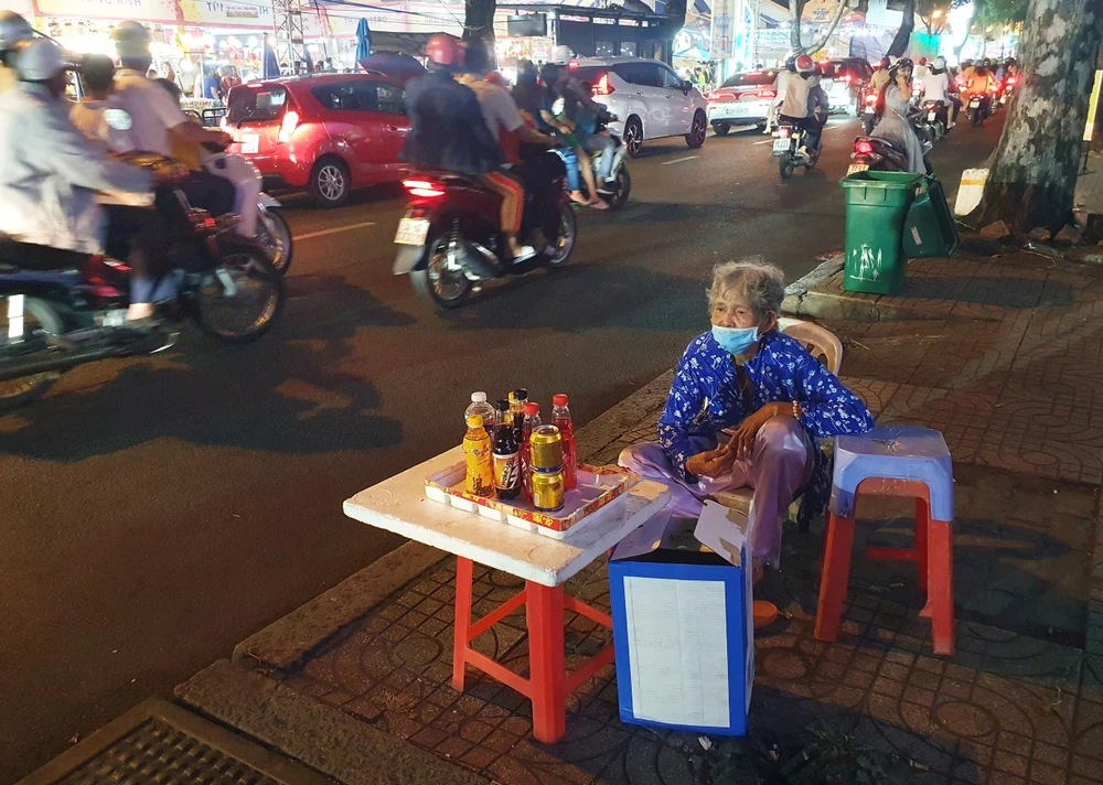 Kế bên con đường tấp nập Lê Lợi (quận 1), bà Phạm Thị Quỳnh bày cái ghế nhỏ bán nước cho bà con, bà cho biết mình chỉ có một mình, bán nước ở đây đã mấy chục năm nay.