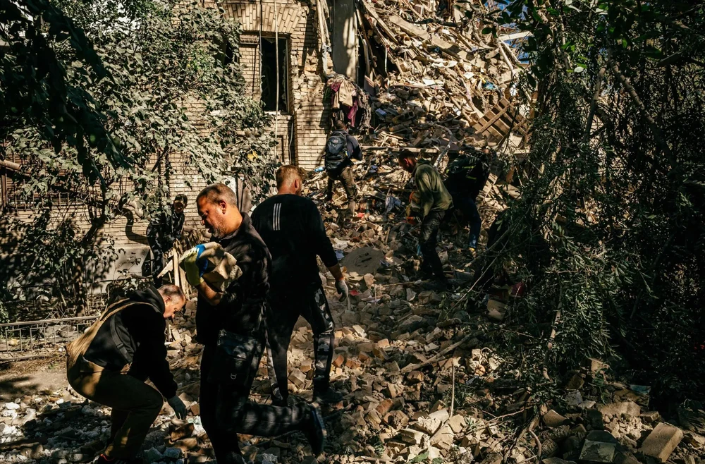 Những người tình nguyện đến dọn dẹp đống đổ nát sau khi Nga pháo kích tỉnh Zaporizhia ngày 6-10. Ảnh: AFP