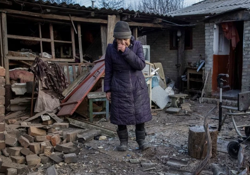 Cụ bà đứng bên cạnh ngôi nhà bị hư hại do pháo kích ở TP Chasiv Yar, tỉnh Donetsk ngày 28-1. Ảnh: REUTERS