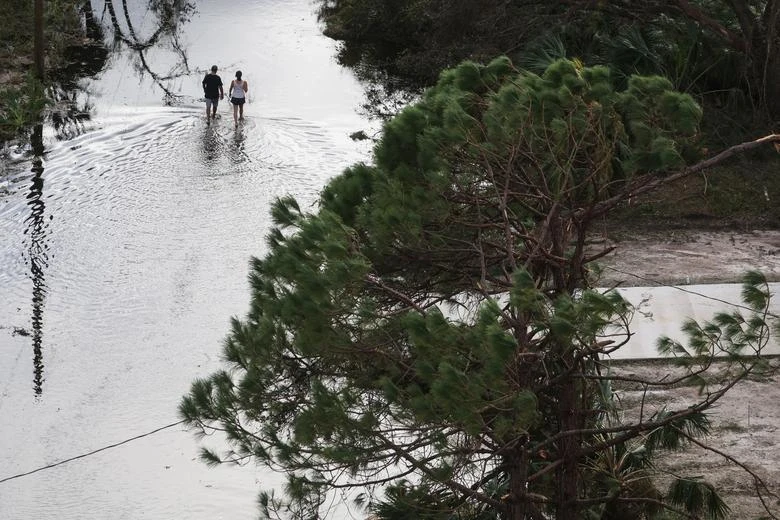 Một cặp đôi đi bộ trên con phố ngập lụt ở thành phố Punta Gorda, quận Charlotte. Ảnh: REUTERS