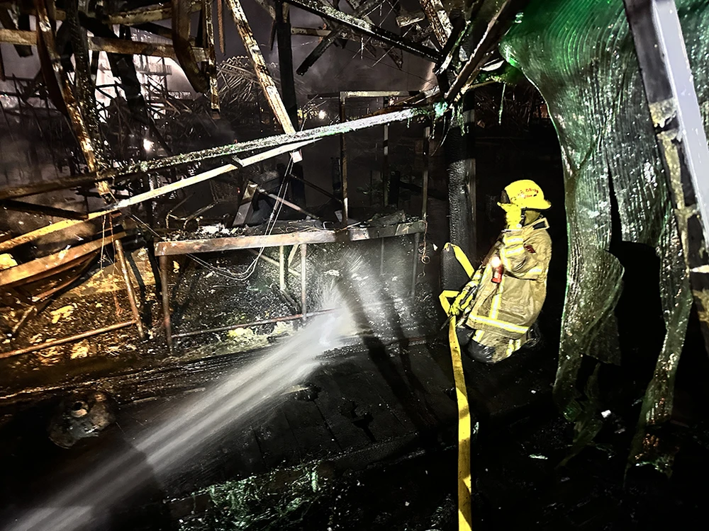 Lính cứu hỏa tiếp tục phun nước vào khu chợ để ngăn ngọn lửa bùng phát trở lại. Ảnh: KHAOSOD ENGLISH