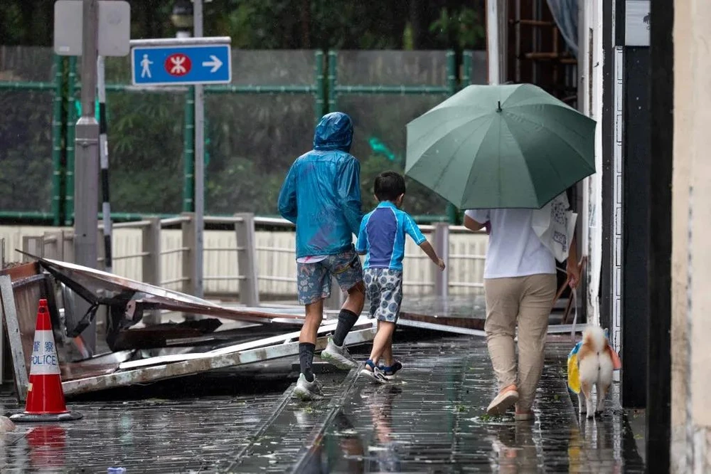 Người dân đi ngang qua các mảnh vỡ khi siêu bão Ragasa quét qua khu Causeway Bay ở Hong Kong ngày 24-9. Ảnh: AFP