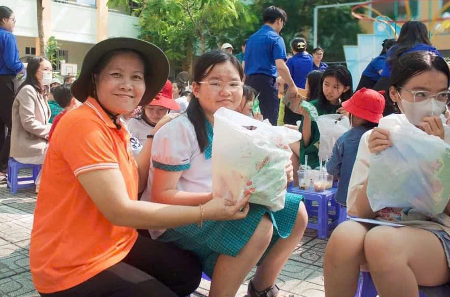 Bà Chi cùng trò chuyện, trao quà quà cho học sinh tại khu phố.