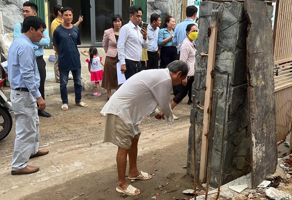Một hộ dân đang tháo dỡ tường rào trước nhà để bàn giao mặt bằng. Ảnh: HỮU ĐĂNG