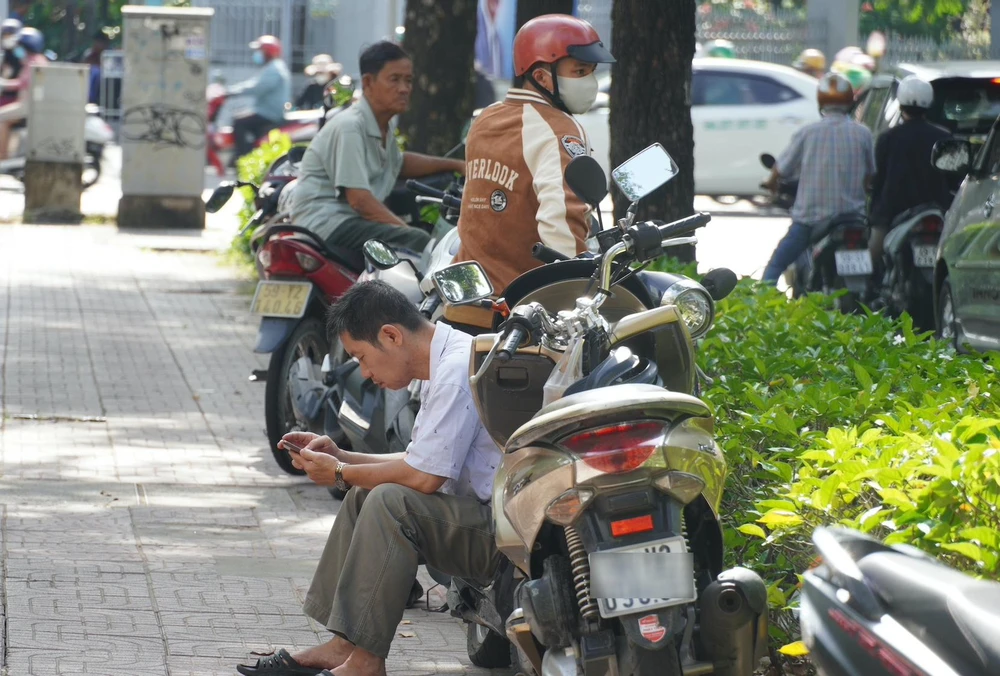 Một người dân đang theo dõi diễn biến phiên xét xử qua điện thoại. Ảnh: HỮU ĐĂNG