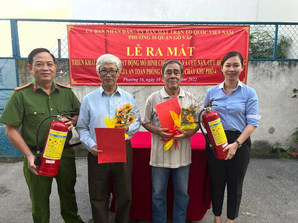 Bà Phan Thị Hoàng Lan, Phó Chủ tịch UBND phường 16 và ông Phan Tấn Hưng, Trưởng Công an phường 16, quận Gò Vấp trao quyết định thành lập tổ liên gia và bình chữa cháy cho hai tổ dân phố thuộc khu phố 4. Ảnh: ĐẶNG LÊ