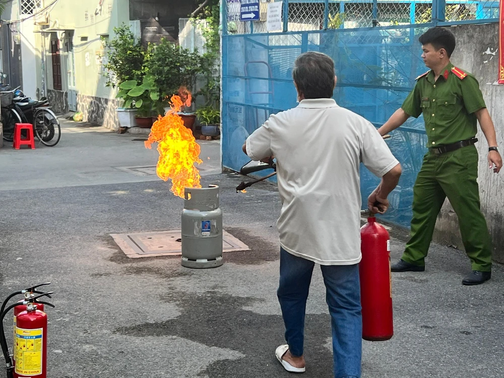 Một bác lớn tuổi trong tổ liên gia thực hành dập tắt đám cháy sau khi được hướng dẫn. Ảnh: ĐẶNG LÊ