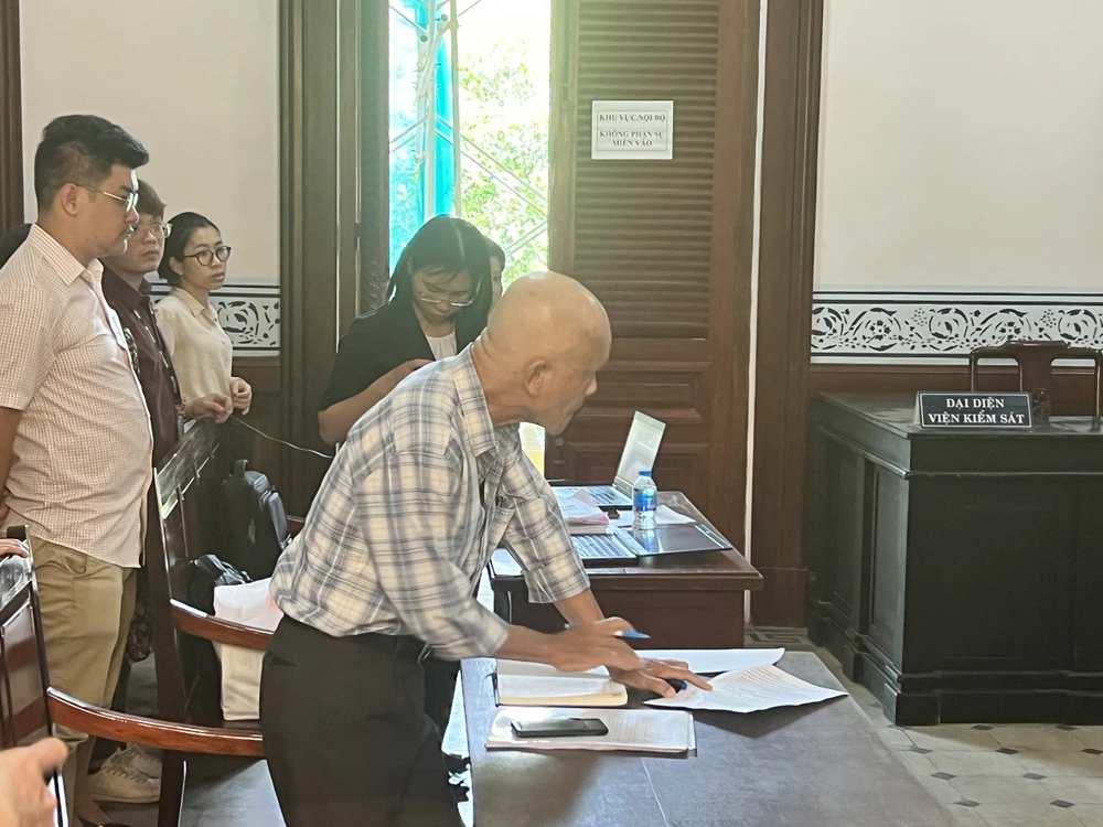 Đại diện theo ủy quyền của nguyên đơn (cầm bút) tại phiên toà. Ảnh: HỮU ĐĂNG