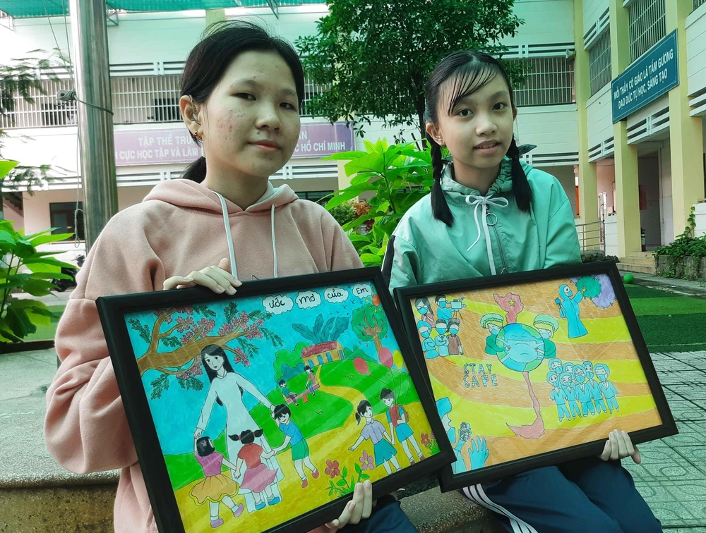 Cháu Lục Tuyết Mai (trái) và cháu Võ Thị Hà Phượng cùng hai bức tranh được bán đấu giá. Ảnh: TRẦN NGỌC