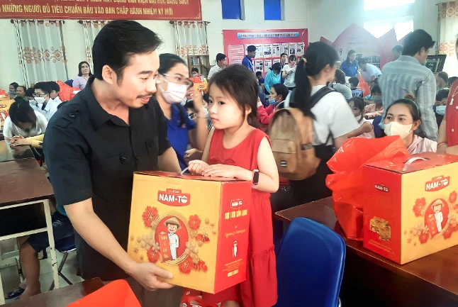 Một em bé nhận quà Tết từ ông Nguyễn Trần Hữu Thắng. Ảnh: PHƯỚC LỢI