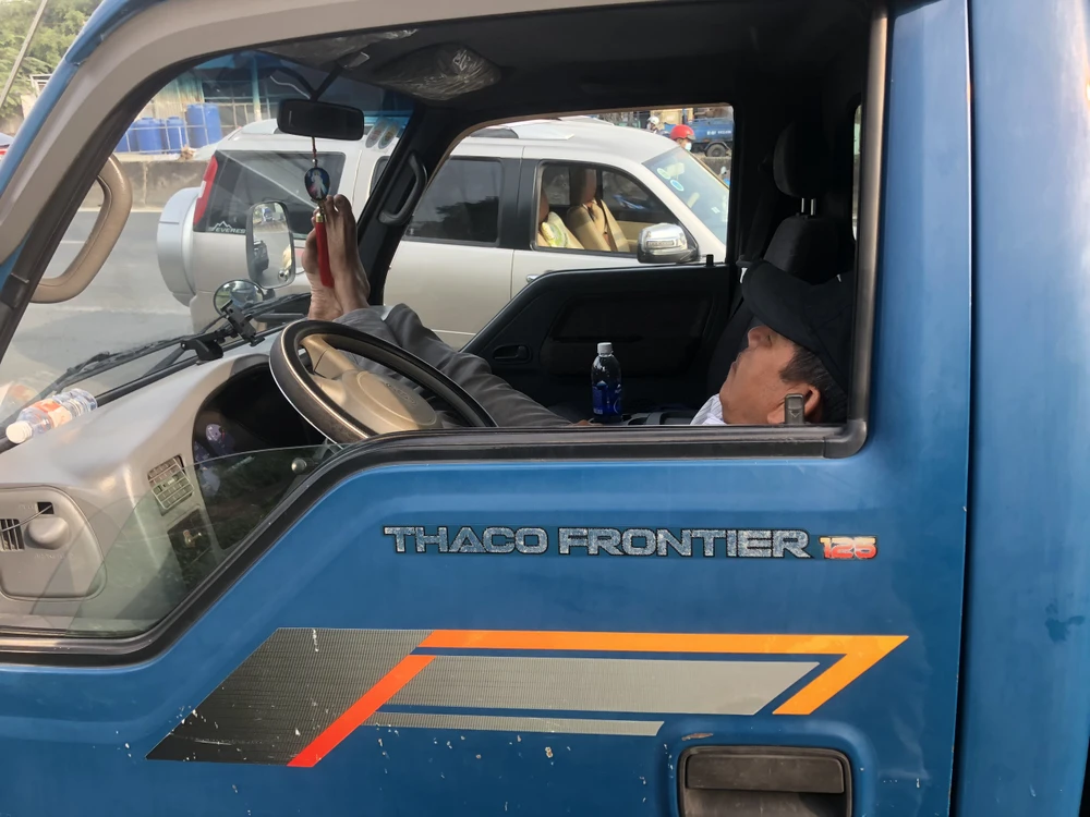 Một tài xế mệt mỏi khi chờ đến lượt đăng kiểm đã ngủ trên xe. Ảnh: HUỲNH DU