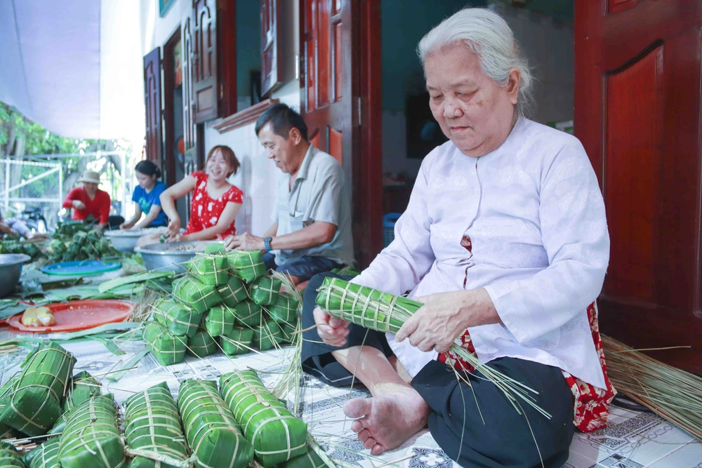Bà Võ Thị Ánh dù 72 tuổi vẫn say mê với nghề gói bánh tét truyền thống. Ảnh: HUỲNH DU Xóm bánh tét Vàm Thủ đỏ lửa dịp tết