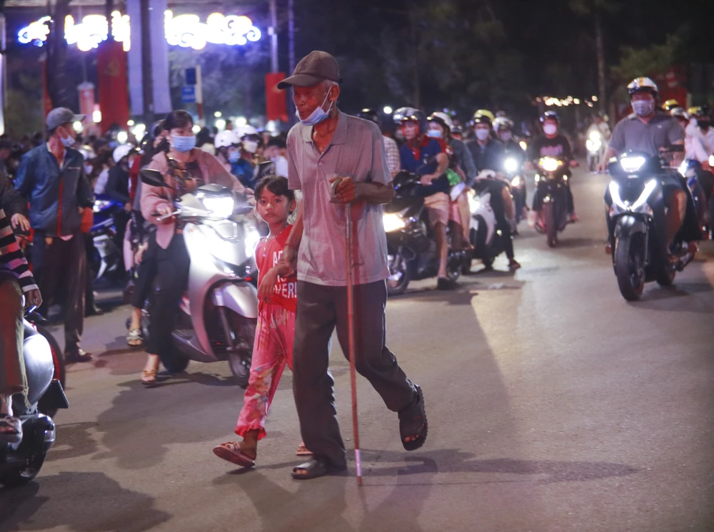 Các bé được ông, bà dẫn cháu tiến gần đến gần sân vận động Long An để xem bắn pháo hoa. Ảnh: HUỲNH DU