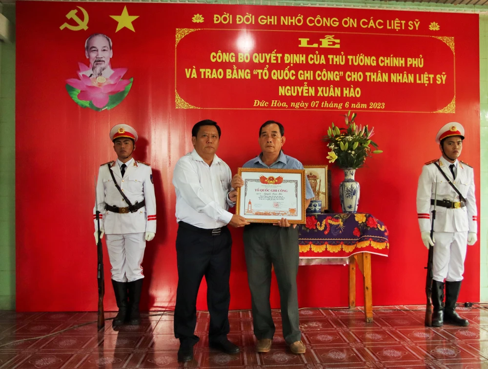 Phó Chủ tịch UBND tỉnh Long An Huỳnh Văn Sơn trao bằng Tổ quốc ghi công cho thân nhân gia đình liệt sĩ Nguyễn Xuân Hào. Ảnh: HUỲNH DU