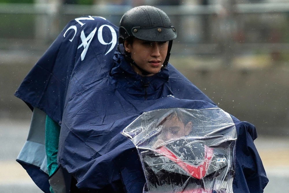 Cơn mưa bất chợt chiều ngày 3-9, khiến nhiều người phải đội mưa để di chuyển tiếp đoạn đường còn lại. Ảnh: HUỲNH DU