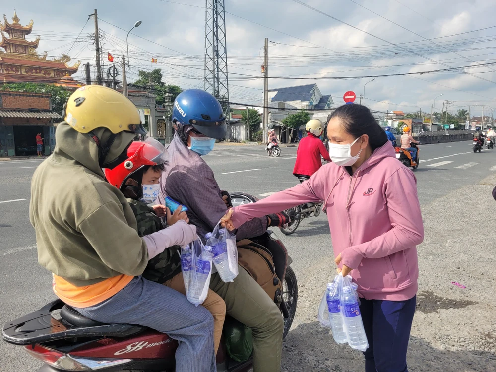 Thành viên nhóm tình nguyện trao nước cho người dân từ miền Tây đi TP.HCM. Ảnh:HD