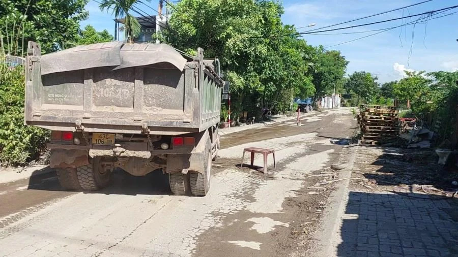Người dân dùng chướng ngại vật đặt ra đường để xe ben giảm tốc độ nhằm bớt bụi. Ảnh: HẢI HIẾU Người dân dùng chướng ngại vật đặt ra đường để xe ben giảm tốc độ nhằm bớt bụi. Ảnh: HẢI HIẾU