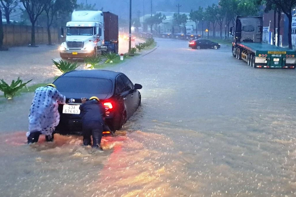 Lực lượng chức năng đẩy một chiếc ô tô bị chết máy để giải tỏa giao thông. Ảnh: HẢI HIẾU