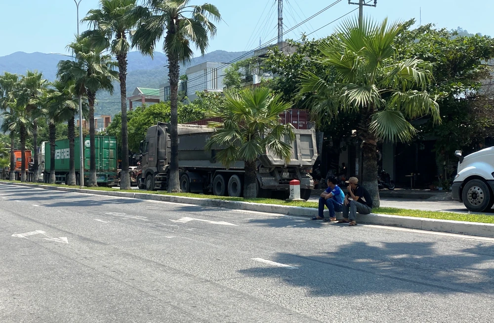 Hai tài xế ngồi ngóng về giao lộ bị chặn, chờ được thông đường. Ảnh: HẢI HIẾU