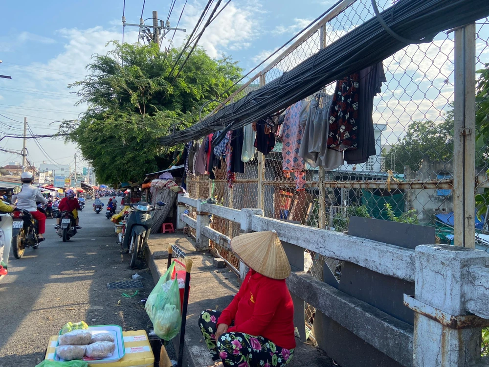 Chị H, ngụ quận Bình Tân, TP.HCM cho biết: Chị buôn bán ở chợ này lâu rồi, nhưng hồi trước chị ngồi ở trước nhà kia bị người ta đuổi đi. Sau thấy nhiều người lên cầu ngồi bán chị cũng bắt chước, thấy không ai nói gì nên chị bán đến giờ. Ảnh: HUỲNH THƠ.