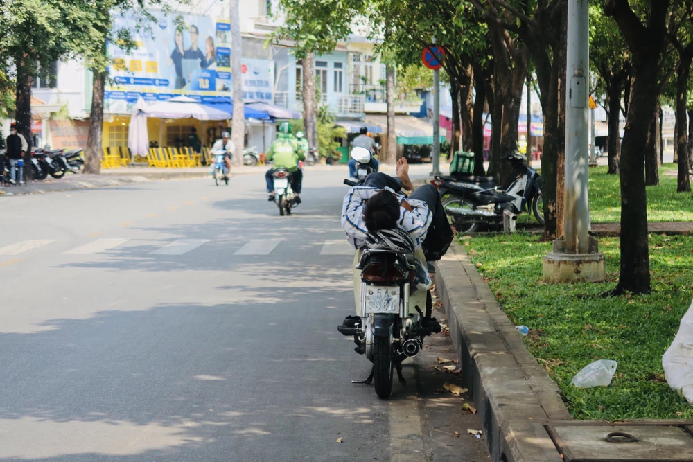 Bóng mát của những tán cây là nơi tránh nắng của người lao động thường xuyên ở ngoài trời như xe ôm, shipper, người bán vé số,... Ảnh: TRẦN MINH