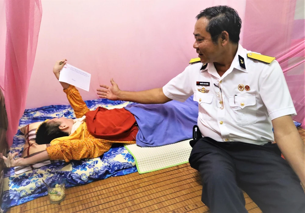 Ông Nguyễn Văn Dũng tặng quà cho chị Đỗ Thị Thanh Phượng, 44 tuổi, mồ côi cha mẹ và nằm liệt tại chỗ từ khi sinh ra. Ảnh: C.T