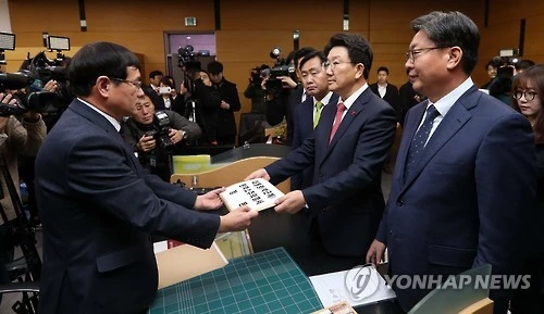 Chủ tịch Ủy ban Tư pháp Quốc hội Hàn Quốc Kwon Seong-dong (trái) trình nghị quyết của quốc hội về việc đề nghị luận tội Tổng thống Park cho một quan chức Tòa án Hiến pháp ngày 9-12. 