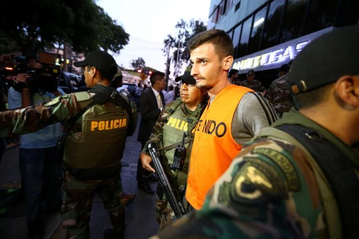 Áp giải nghi can. Ảnh: REUTERS