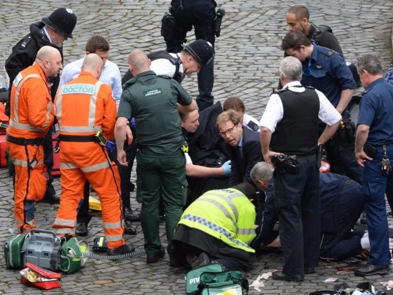 Nghị sĩ Anh (mang kính) giúp cứu chữa người bị thương trên đường. Ảnh: PA