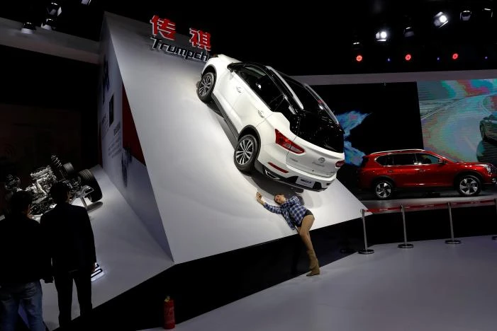 Một phụ nữ chụp hình với mẫu ô tô Trumpchi GS4 của GAC Group trưng bày tại Triển lãm ô tô Thượng Hải, Trung Quốc ngày 20-4. Ảnh: REUTERS