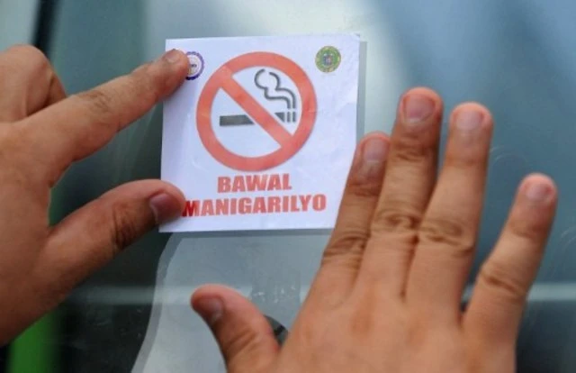 Nhân viên y tế Philippines dáng áp phích “Không hút thuốc” trên kính xe buýt, trong một chiến dịch kêu gọi không hút thuốc năm 2010. Ảnh: AFP