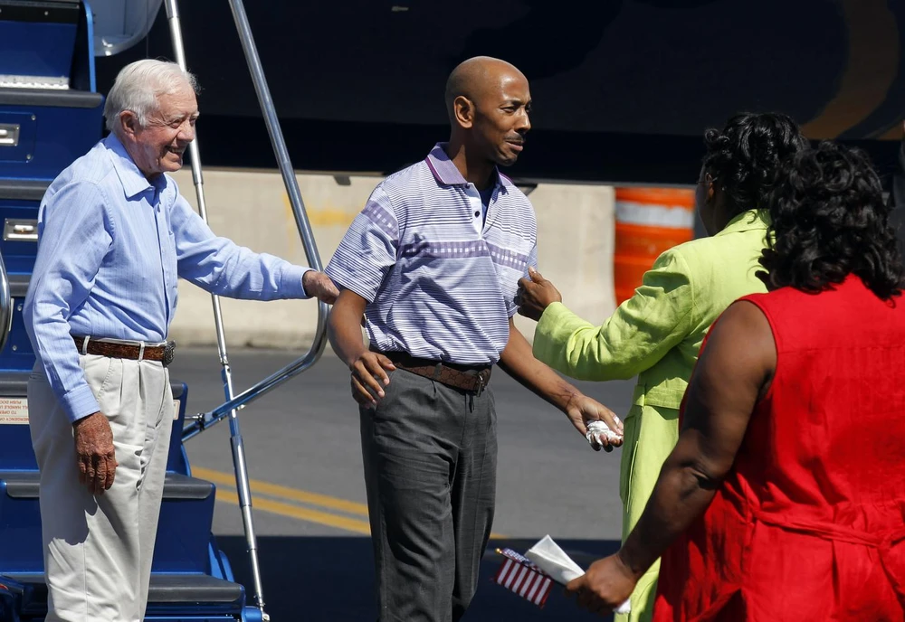 Anh Aijalon Mahli Gomes (giữa) được gia đình mừng đón tại sân bay sau khi được cựu Tổng thống Mỹ Jimmy Carter (trái) đưa về Mỹ. Ảnh: REUTERS