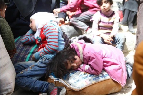 Trẻ em mệt mỏi chờ sơ tán khỏi thị trấn Douma, Đông Ghouta, ngoại ô thủ đô Damacus (Syria) ngày 22-3. Ảnh: REUTERS