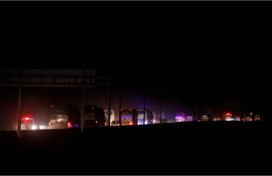 Đoàn xe chở các tay súng nổi dậy và người thân ở thị trấn Harasta, Đông Ghouta, ngoại ô thủ dô Damacus (Syria) rời đi vào chiều tối 22-3. Ảnh: REUTERS